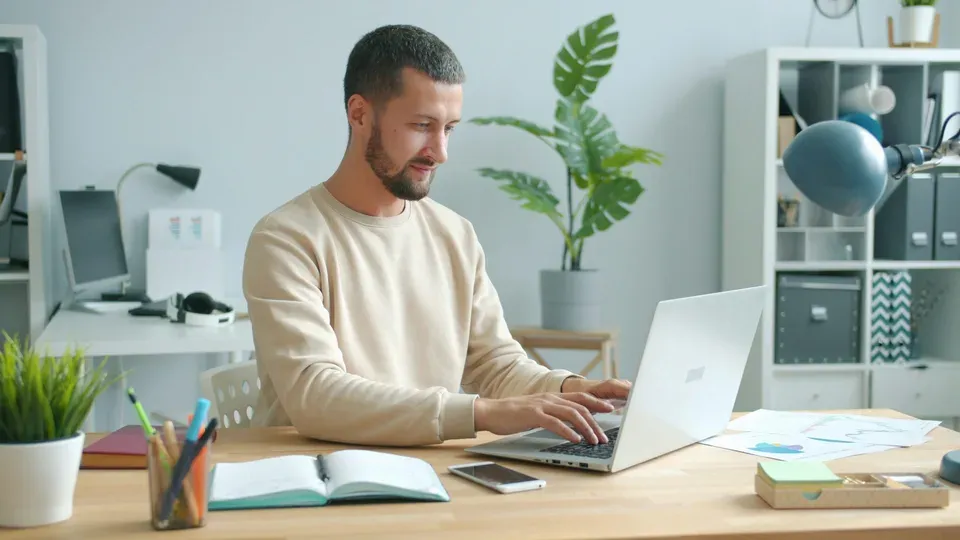 Hands typing on laptop keyboard in home office