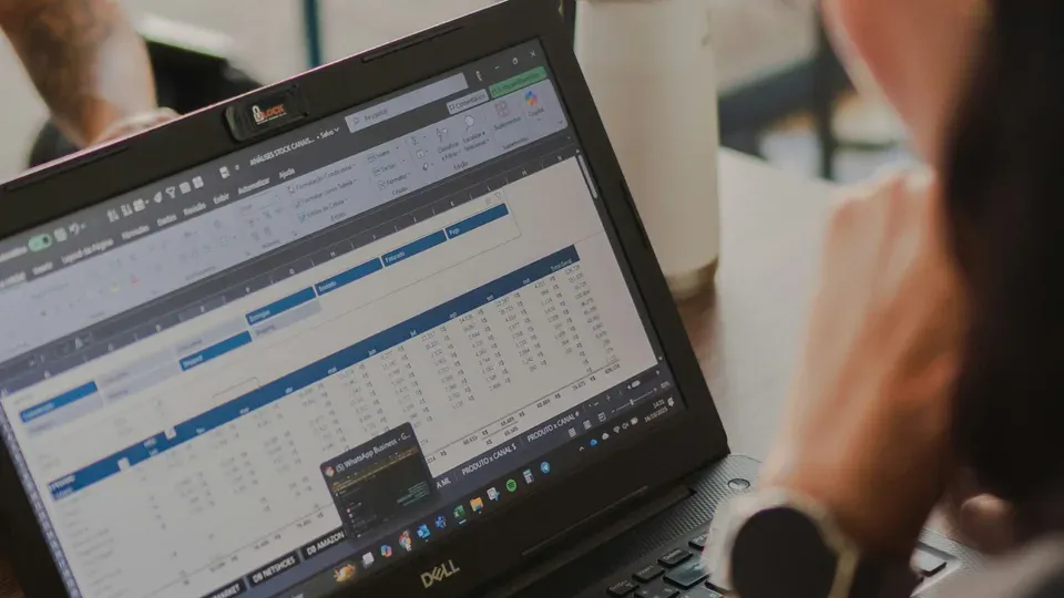 Person working at desk with laptop and data analysis materials