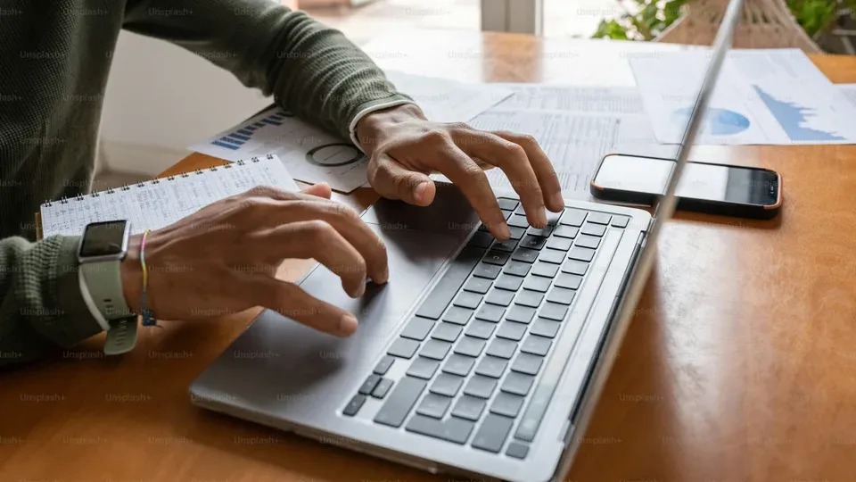 Person typing on keyboard while working on laptop at desk
