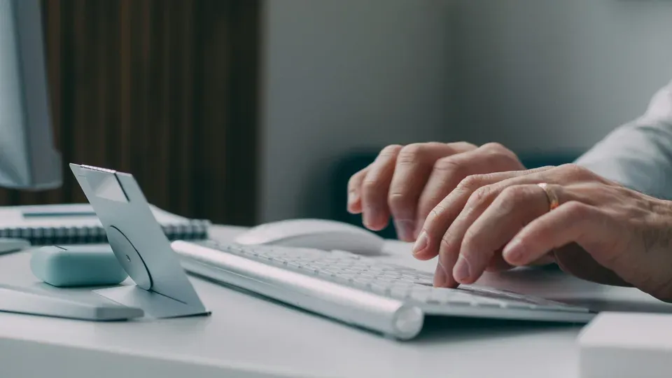 Person typing on keyboard while working at computer workspace