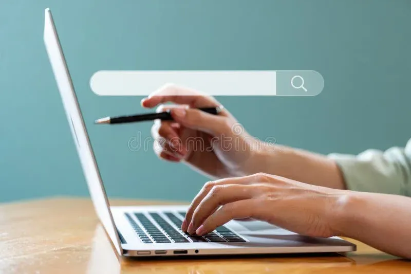 Hands typing on laptop keyboard with search interface visible