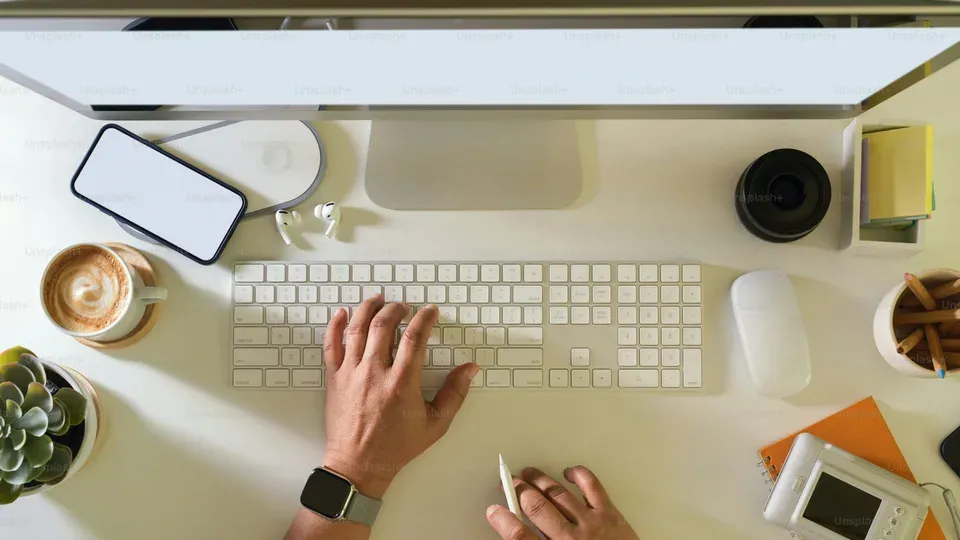 Hands typing on keyboard at a clean workspace desk