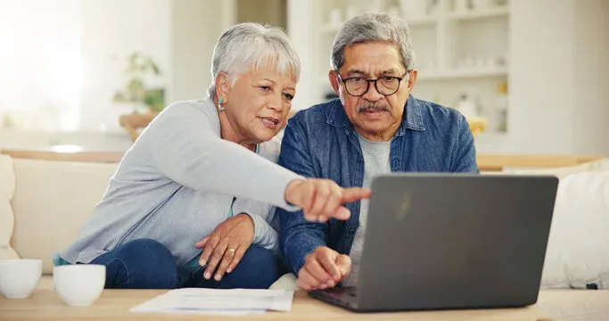 Senior couple researching senior living options on a laptop together