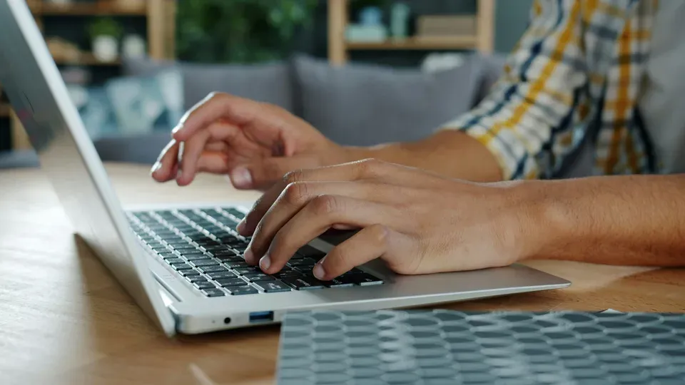 Hands typing on keyboard at a clean desk workspace