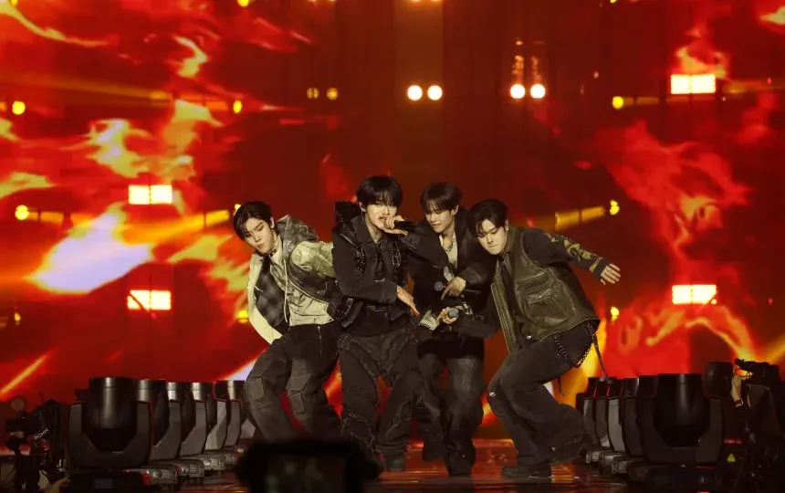 K-pop boy band performing on stage with concert lighting and choreography
