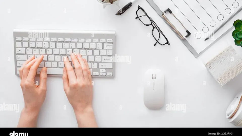 Hands typing on keyboard at a professional workspace desk