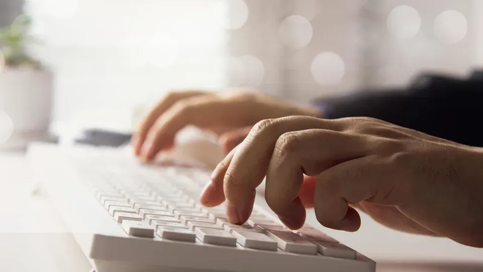 Hands typing on keyboard at a professional workspace desk