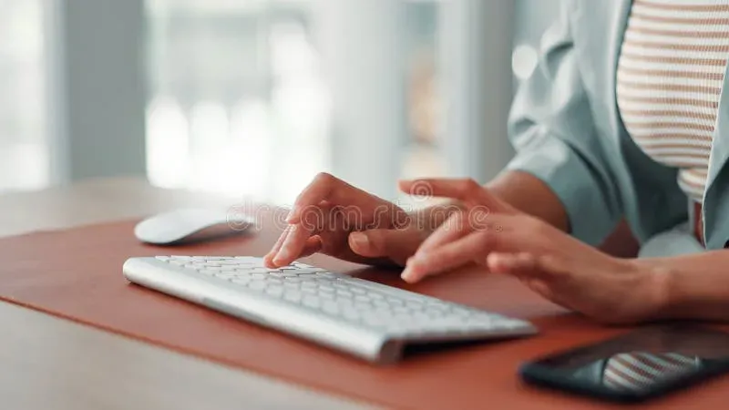 Hands typing on keyboard at desk while creating SEO content