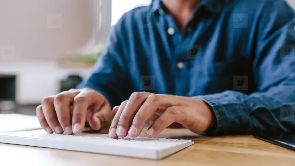 Close-up of hands typing on a laptop keyboard during work