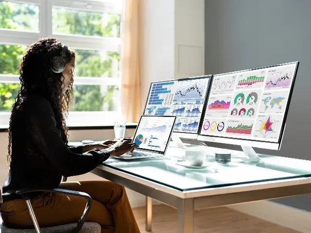 Person at desk reviewing analytics dashboard on multiple monitors