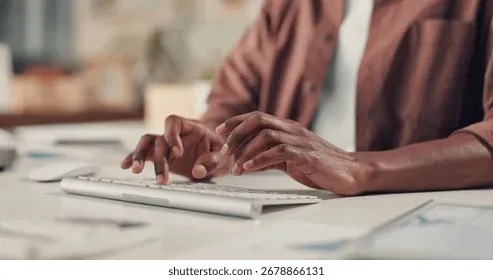 Hands typing on keyboard while creating content at a workspace
