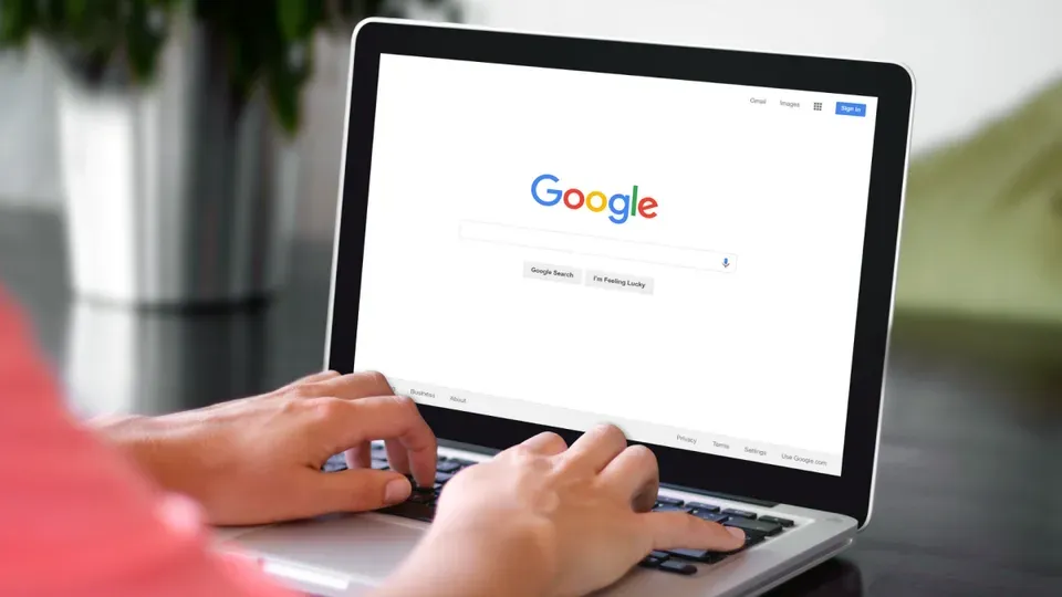 Person typing a search query on a laptop with Google search visible