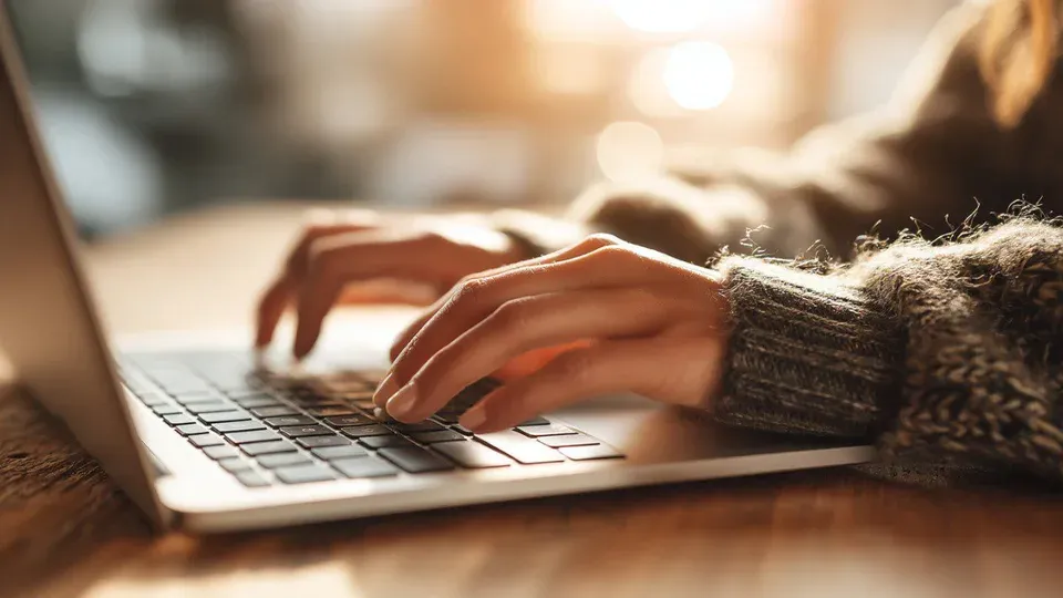 Hands typing on laptop keyboard during active content creation work